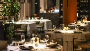 Un restaurante con mesas redondas dispuestas para comer, con manteles blancos y centros de mesa con velas.