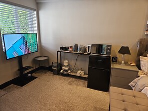 Cozy living space with a flat-screen TV, kitchenette, and comfortable sofa.