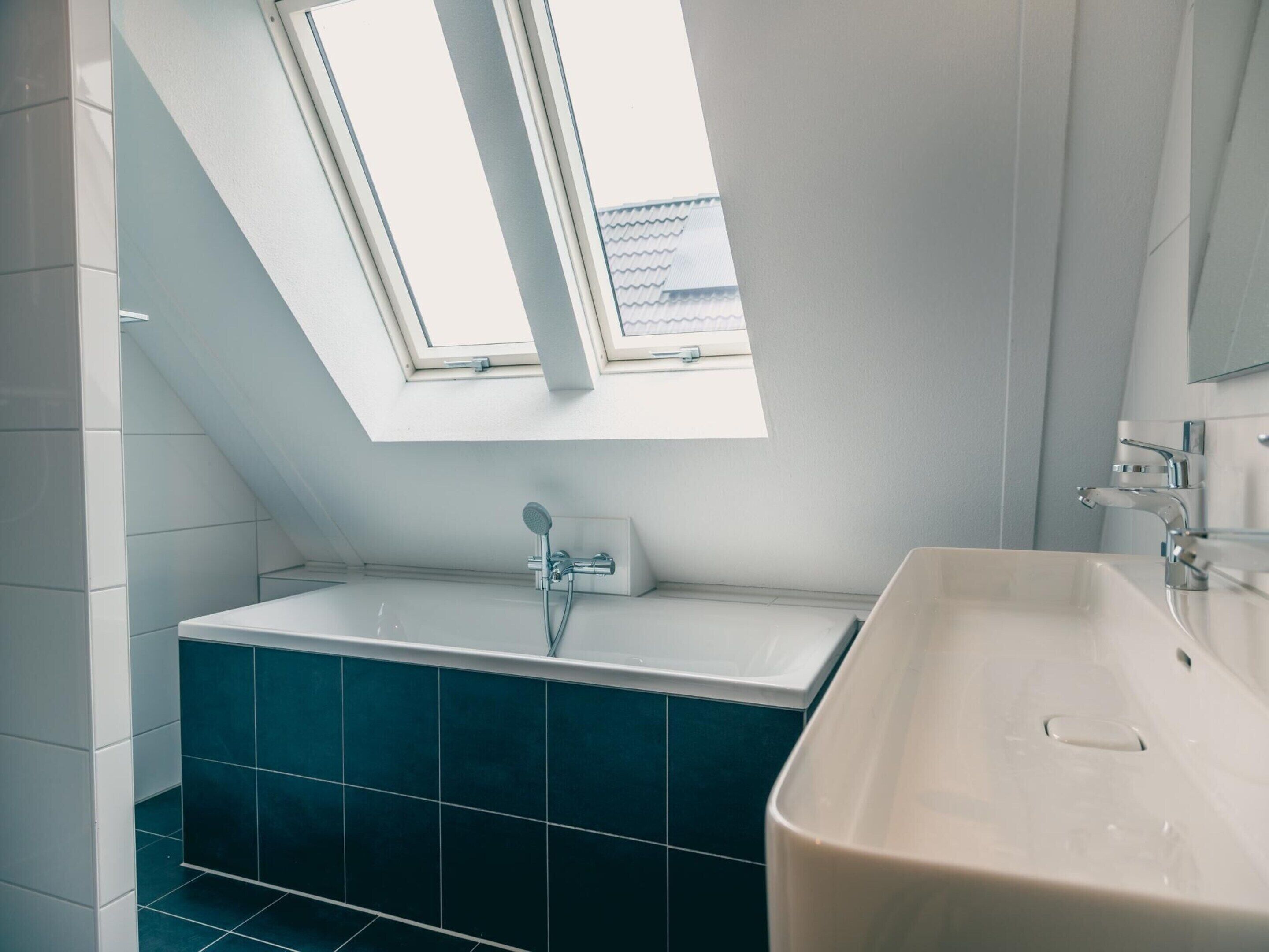 A modern bathroom with a skylight, a freestanding bathtub, and a sink.