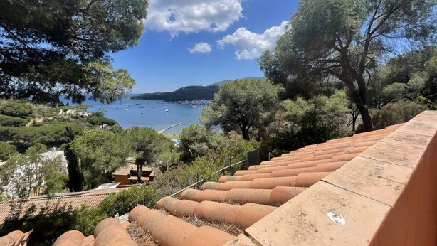 Une vue sur la côte, avec des terrasses en gradins descendant vers une étendue d’eau, le tout entouré d’arbres et de bâtiments.
