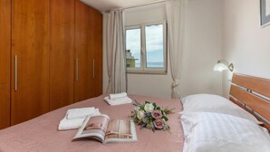 Une chambre à coucher avec un lit, une fenêtre, un ventilateur de plafond et une armoire en bois.