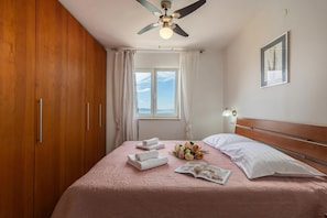 A bedroom with a bed, a ceiling fan, a window with curtains, and a framed picture on the wall.