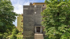 Un immeuble à plusieurs étages, doté d’une façade en béton, d’un escalier central et d’une petite porte d’entrée.