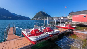 Un quai où sont amarrés plusieurs petits bateaux, une jetée en bois et un bâtiment à la façade rouge.