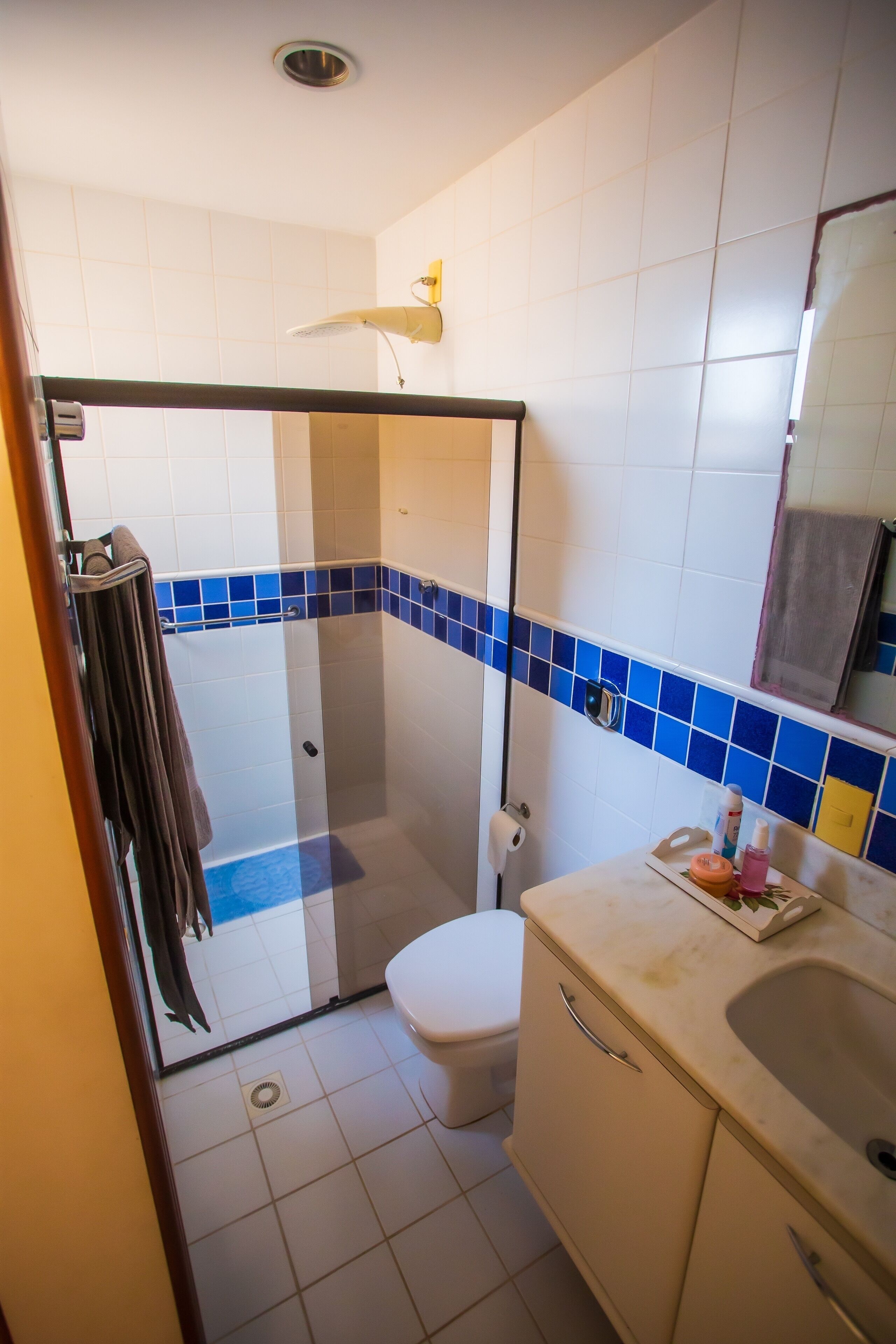 A bathroom with a glass shower enclosure, a toilet, a sink, and a mirror.