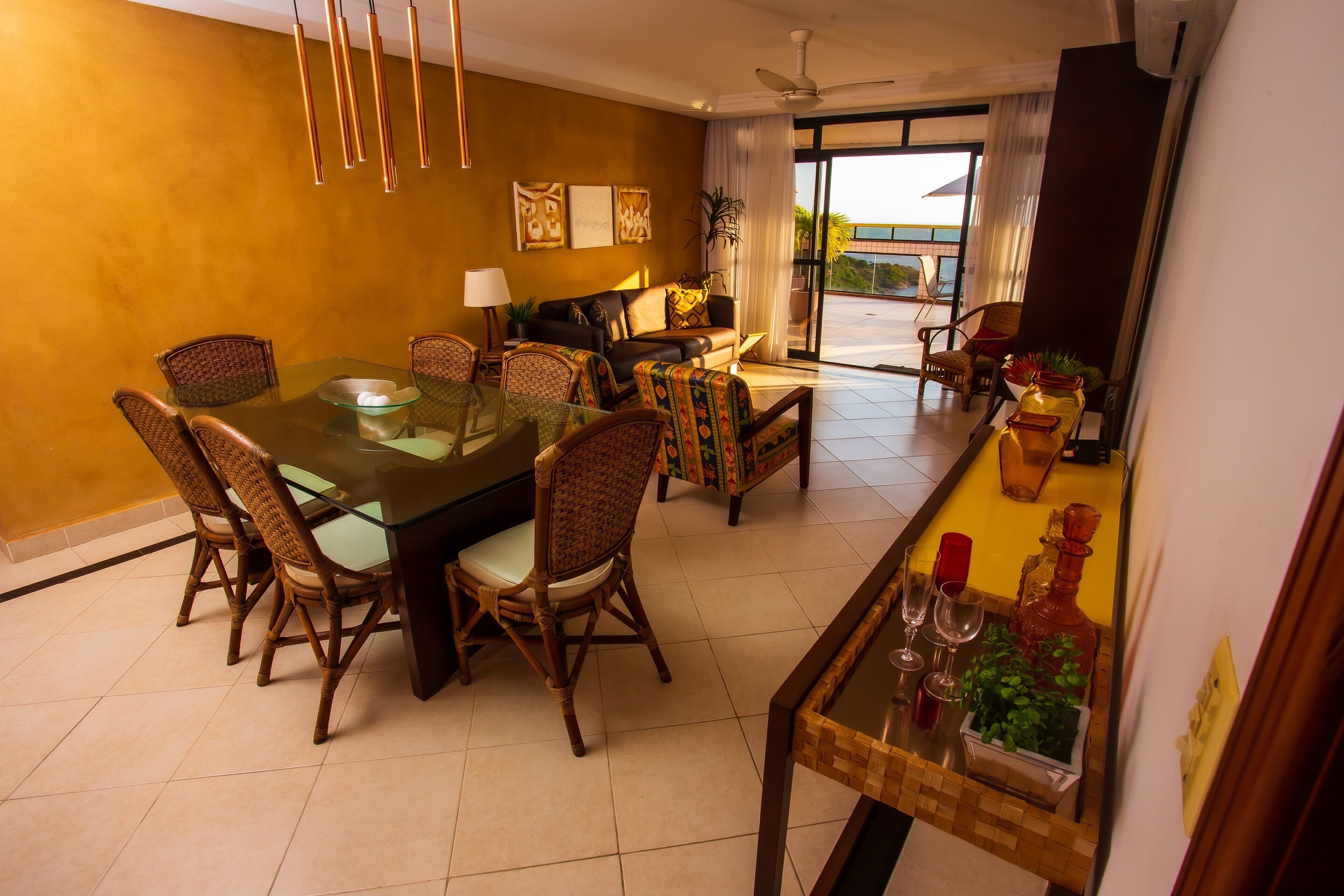 A dining area with a glass table, wicker chairs, a sofa, and a coffee table.