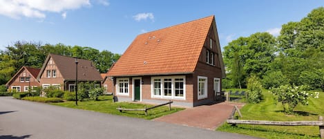 A two-story house with a red-tiled roof, a brick exterior, and a green door.