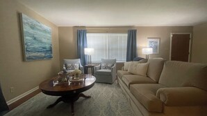 A living room with a round coffee table, two armchairs, a sofa, a window with curtains, and a painting on the wall. - Spacious home near medical / college (Tyler)