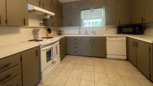A kitchen with a stove, oven, microwave, sink, and cabinets. - Spacious home near medical / college (Tyler)