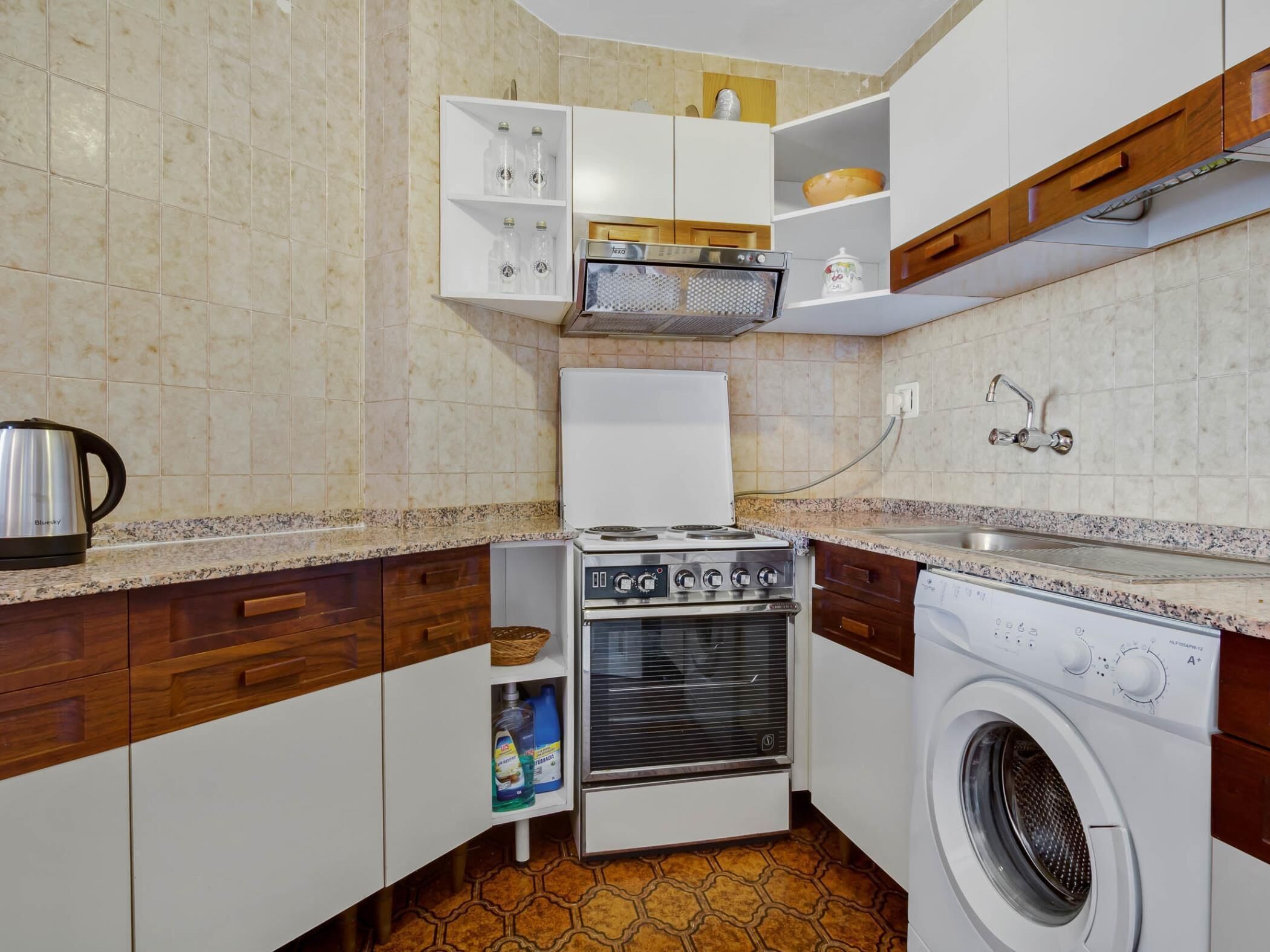 Een praktische keuken met een fornuis, oven, magnetron en wasmachine.