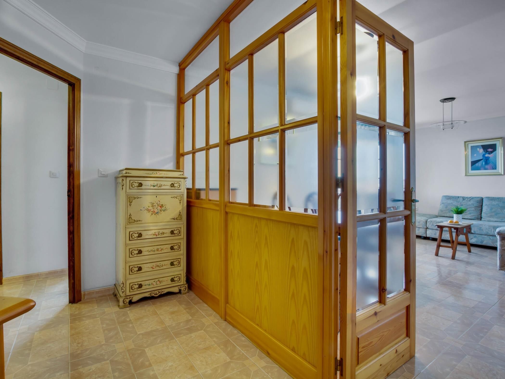 A room with a wooden wardrobe, a sofa, and a small table.