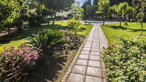A garden pathway leading to a pool area surrounded by lush greenery and trees. - El Rocio 7E1 - Terrace, Swimming Pool, Sea Views (Torremolinos)