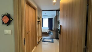 A hallway leading to a bedroom with a bed, a nightstand, and a window with curtains. - RoomQuest Hua Hin Lahabana (Hua Hin)