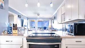 A modern kitchen with white cabinets, a stove, and a microwave.