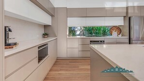 A modern kitchen with built-in appliances, a large window with a view of greenery, and a clean, minimalist design. - Luxe Haven (Moama)