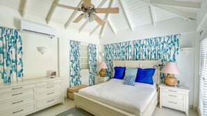Une chambre à coucher avec un grand lit, des meubles blancs et des rideaux à motifs bleus.