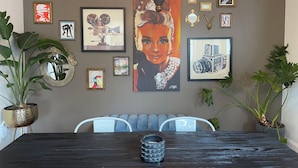 Un comedor con una mesa de madera oscura, dos sillas, una araña y varias obras de arte enmarcadas en la pared.