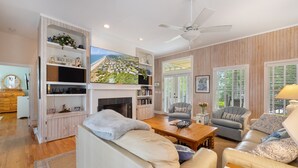 A spacious living room with a fireplace, comfortable seating, and a television. - Screened Porches, Decks, Rockers, Hammocks And An Upstairs Balcony With Ocean Views 5 Bedroom Home by Peace Vacations (Georgetown)