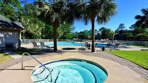 A swimming pool area with lounge chairs, palm trees, and a house in the background. - Fifty-seven Sea This Spacious And Beautiful Condo Overlooking Pond And 4th Hole 3 Bedroom Condo by Peace Vacations (Pawleys Island)
