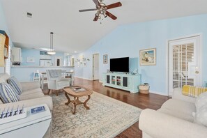 A living room with a sofa, a coffee table, a TV, and a ceiling fan. - True Blue On 10th Hole, A Perfect Retreat For Golf Enthusiasts And Those Seeking A Relaxing Getaway 3 Bedroom Condo by Peace Vacations (Pawleys Island)
