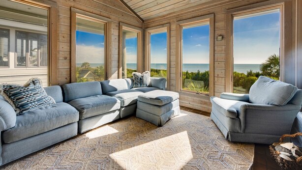 Amplia sala de estar con un sofá seccional grande, un sofá más pequeño y una chaise longue, todos orientados hacia una ventana grande con vistas panorámicas.