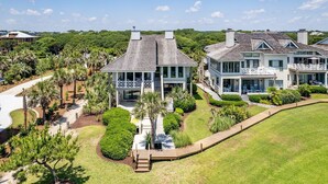 Una casa grande y moderna con un porche espacioso, varias terrazas y jardines exuberantes.