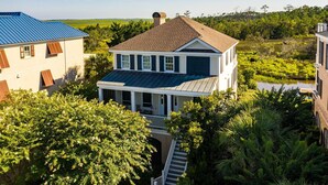 A two-story house with a covered porch and a view of a marshy area. - Delightful, Low Country Home With Dock On Debordieu Channel 4 Bedroom Home by Peace Vacations (Georgetown)