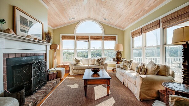 A spacious living room with a fireplace, a large window, and a cozy seating area. - Delightful, Low Country Home With Dock On Debordieu Channel 4 Bedroom Home by Peace Vacations (Georgetown)