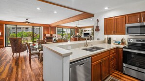 A modern kitchen with wooden cabinets, stainless steel appliances, and a large island with a dishwasher.