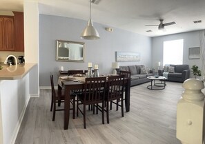 Una sala de estar moderna con comedor, paredes grises, suelo de madera y un ventilador de techo.
