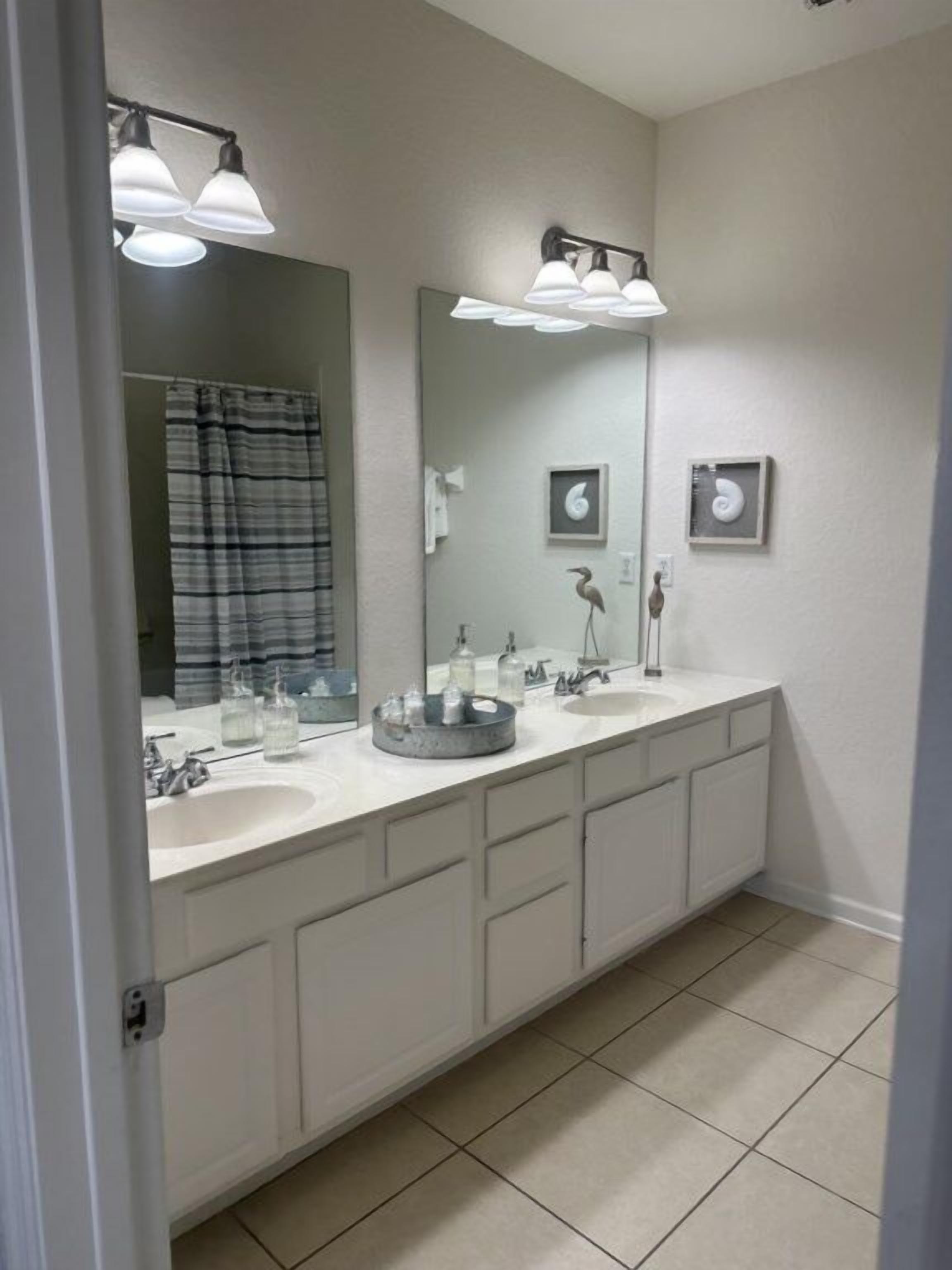 A bathroom with two sinks, a large mirror, and a towel rack.