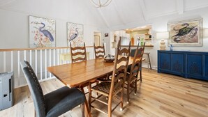 A dining area with a wooden table and chairs, a chandelier, and wall art. - Spacious Second-row Home With Ocean Views In Debordieu, Pet Friendly! 7 Bedroom Home by Peace Vacations (Georgetown)