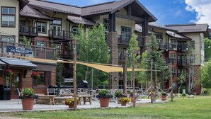 A multi-story hotel with outdoor seating and potted plants. - Base Camp 304 1 Bedroom Condo by RedAwning (Granby)