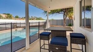Un portico coperto con una piscina, due poltrone in vimini con cuscini e un tavolo.
