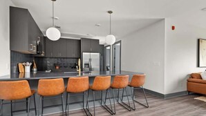 Une cuisine moderne dotée d’un îlot central, de tabourets de bar et de luminaires suspendus.