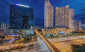 A modern hotel with a glass facade, located in a bustling urban area with high-rise buildings and busy streets. - Vinhomes D'Capitale - Quylodge (Hanoi)