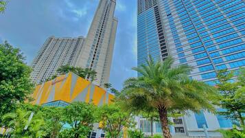 A modern building complex with high-rise structures and a well-maintained garden area with palm trees.