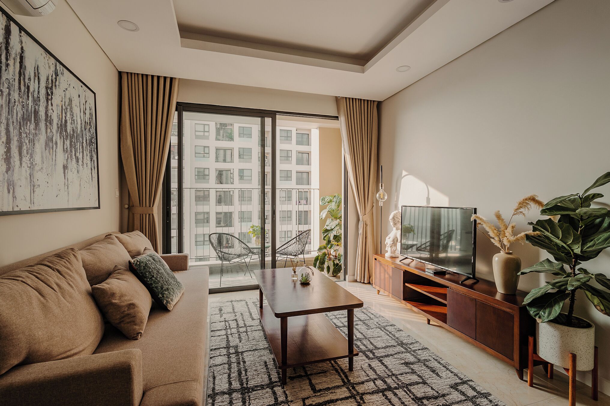 A modern living room with a sofa, a coffee table, a TV, and a large window with curtains.