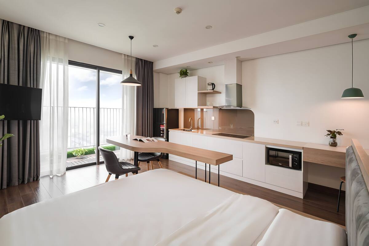 Una habitación de hotel moderna con una cama grande, un escritorio y una kitchenette.