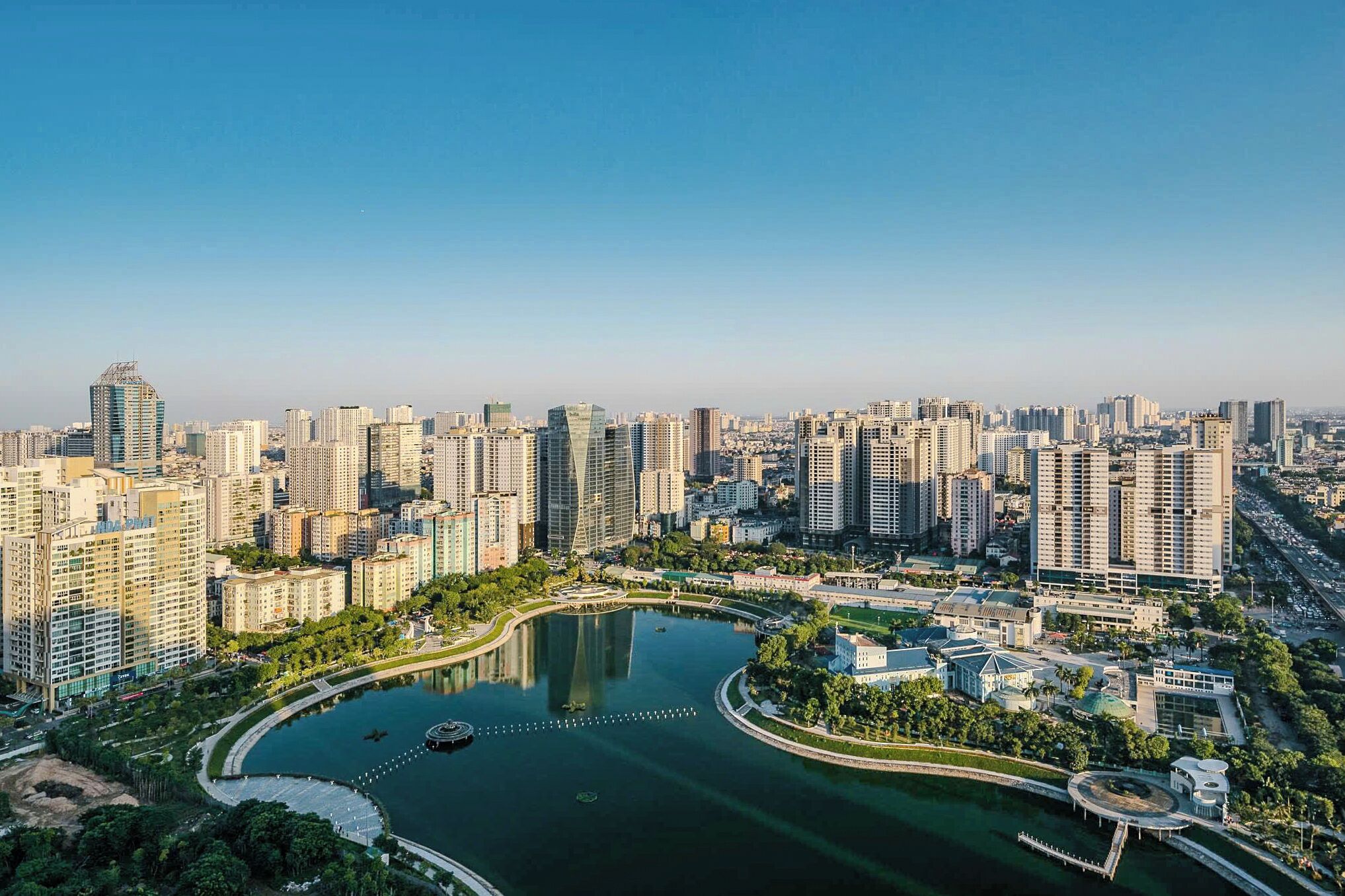 Un paisaje urbano con edificios altos, un lago central y un parque circular.