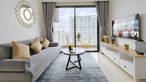 Un salon moderne avec un canapé gris, une table basse ronde et un téléviseur posé sur un meuble en bois.