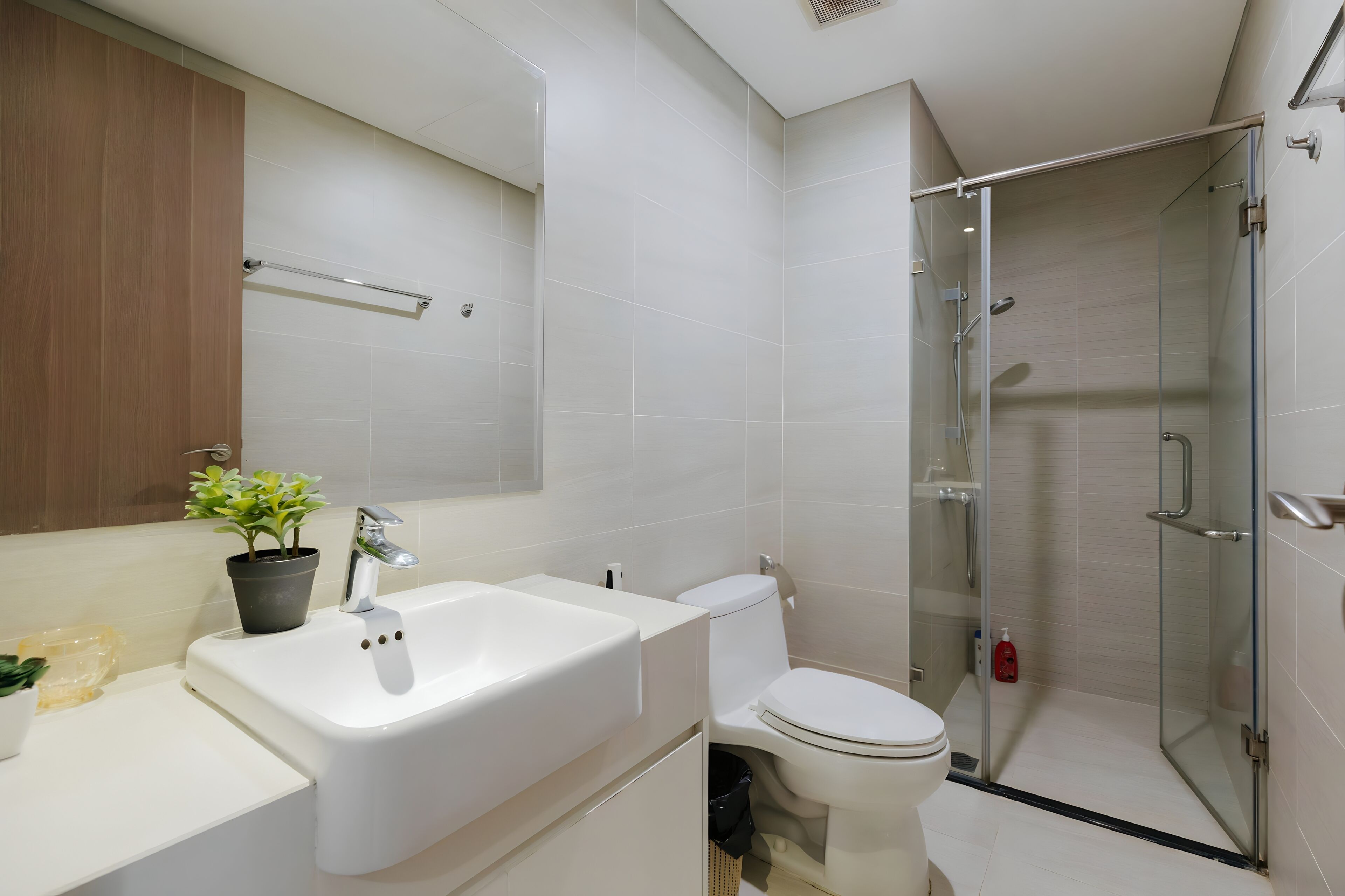 A modern bathroom with a white sink, toilet, and glass-enclosed shower.