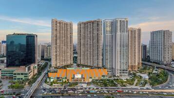 A high-rise residential building complex with multiple apartment buildings, a central commercial building, and a busy urban street with vehicles.
