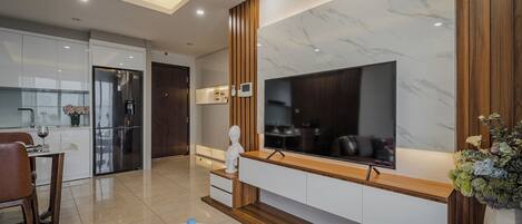 A modern kitchen with a built-in refrigerator, a dining area with a table and chairs, and a living area with a TV and decorative items.