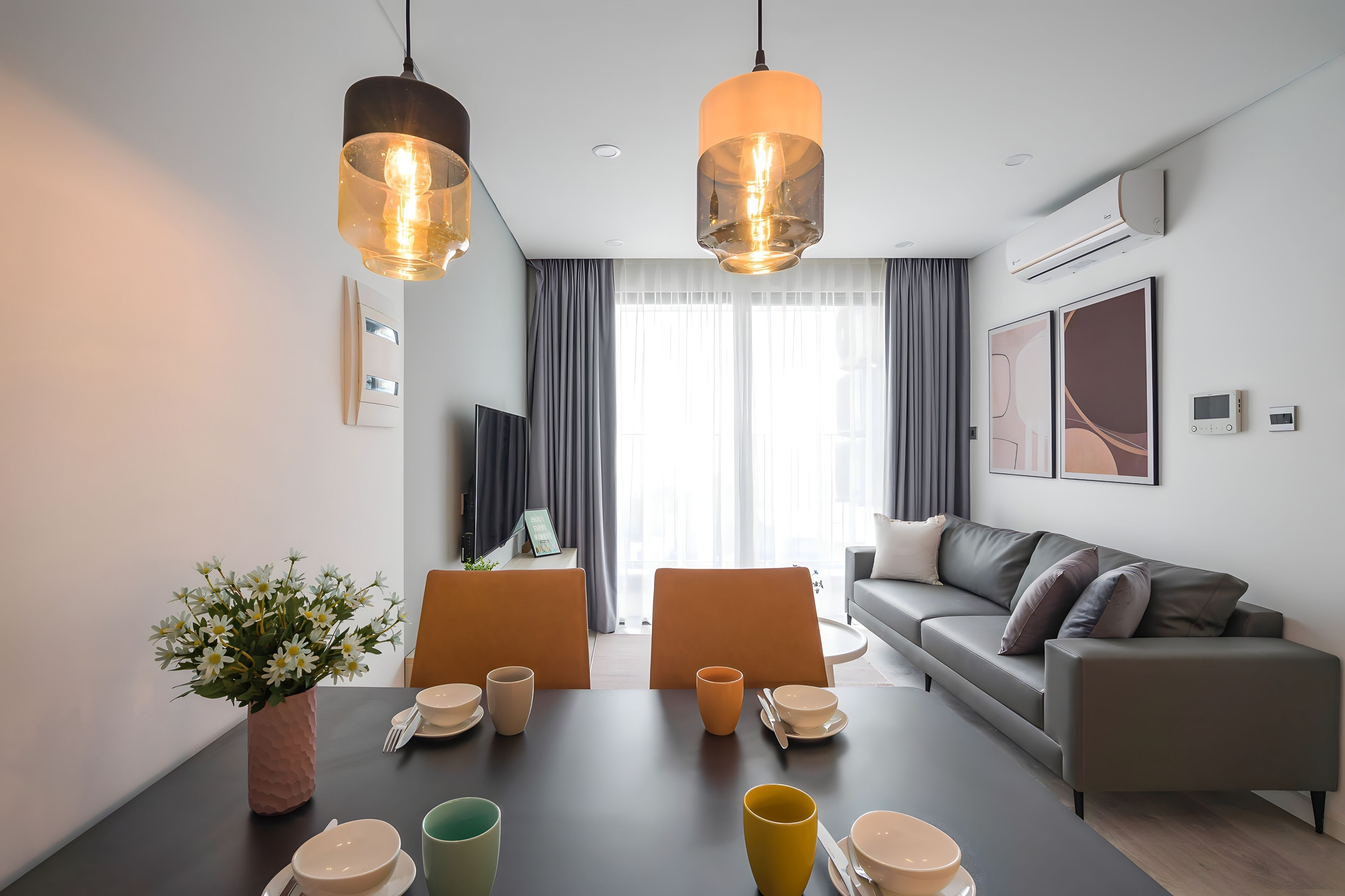 Un salon moderne avec un canapé, une table à manger et des luminaires suspendus.