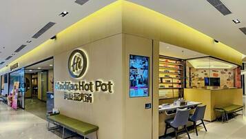 A restaurant named 'Hot Pot' with a yellow and white color scheme, a seating area with tables and chairs, and a counter with a menu display.