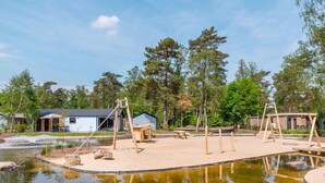 Un parc au bord du lac, avec des balançoires en bois, une table de pique-nique et un petit chalet.
