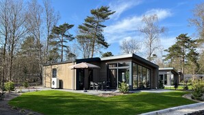 Une maison moderne dotée d’un patio, d’un espace salon extérieur et d’un petit étang.