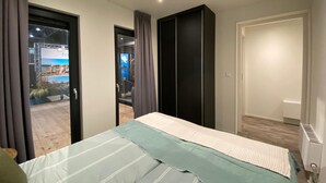 Une chambre avec un lit, une armoire, une porte donnant sur un balcon et un radiateur.