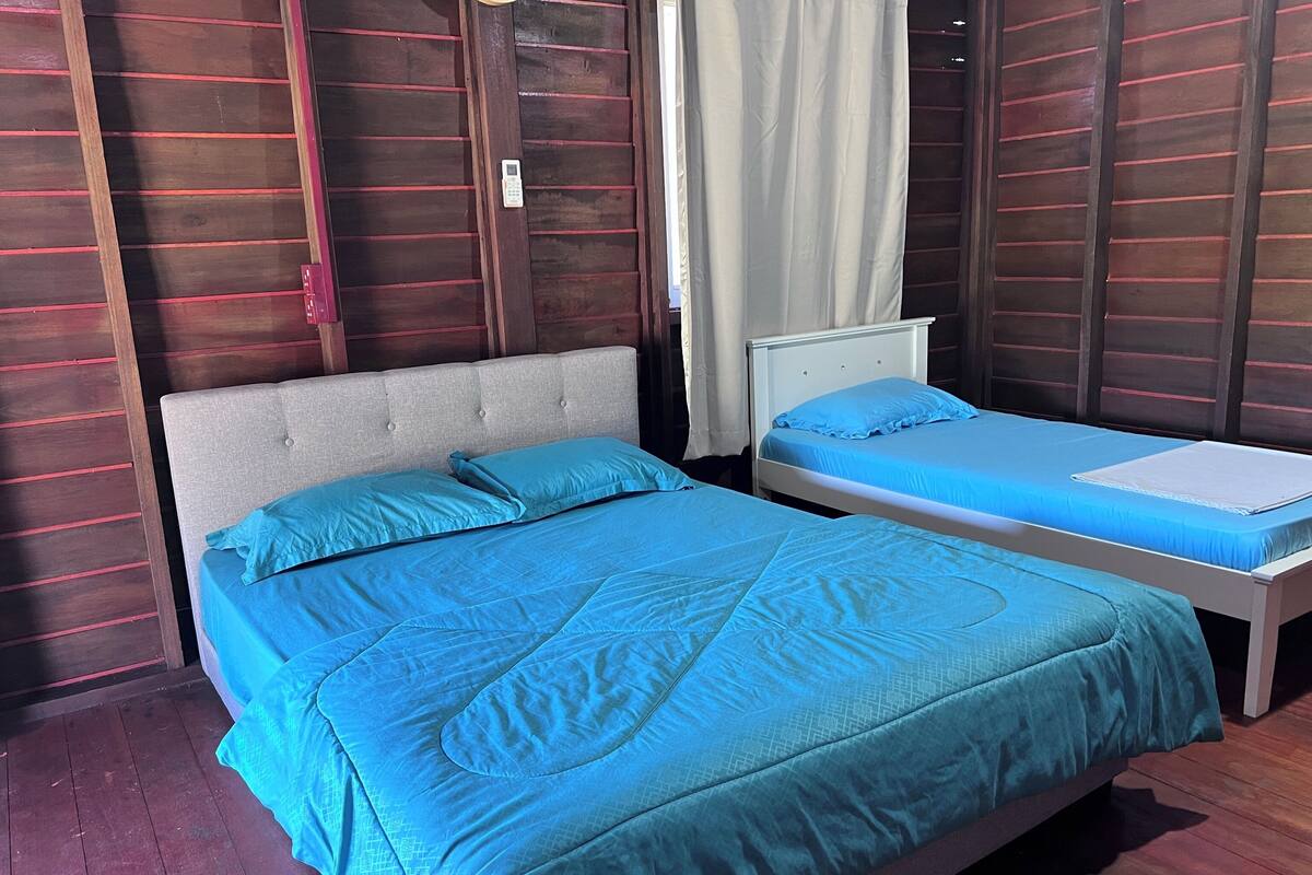 A bedroom with a large bed, a smaller bed, and a nightstand.